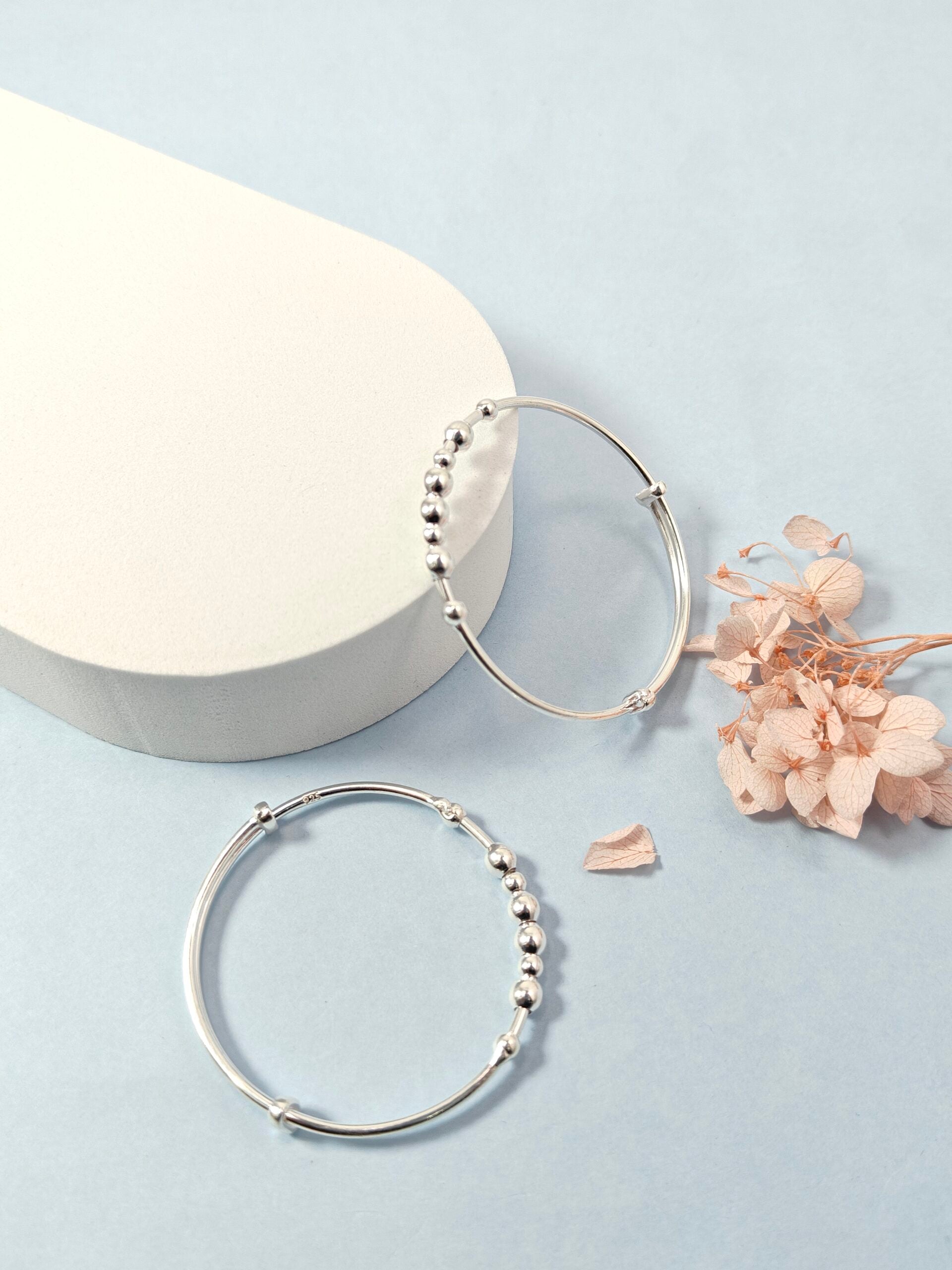 Silver hoop earrings with bead detailing on a light blue background